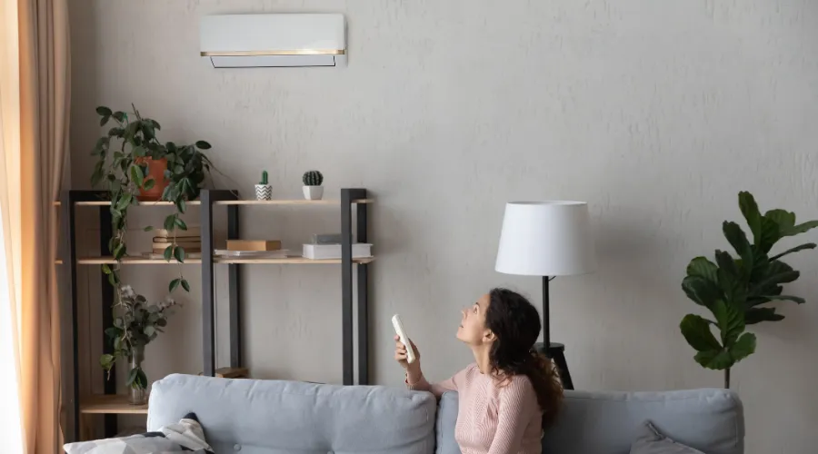 Woman Using Remote To Control Ductless Wall Ac